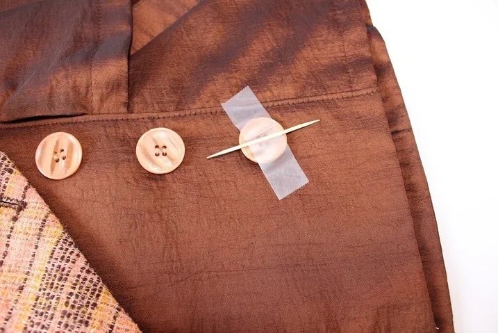 Place a straight pin or a toothpick on the button between the holes.