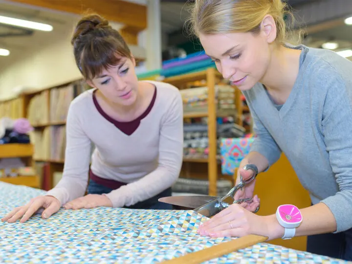 woman cutting fabric in fabric store