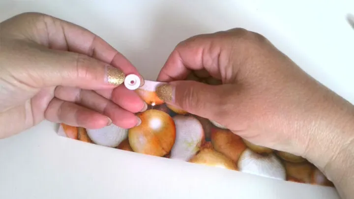 Push the prong of the snap cap from the front side of the flap to the back through the hole.