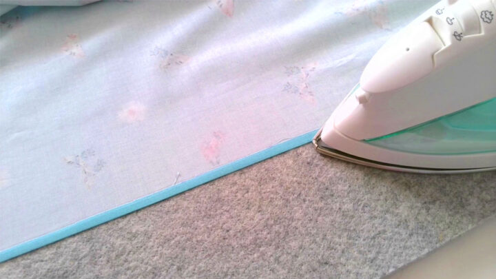 turn under the top edge of the fabric ⅜ “ and pressing it flat. 