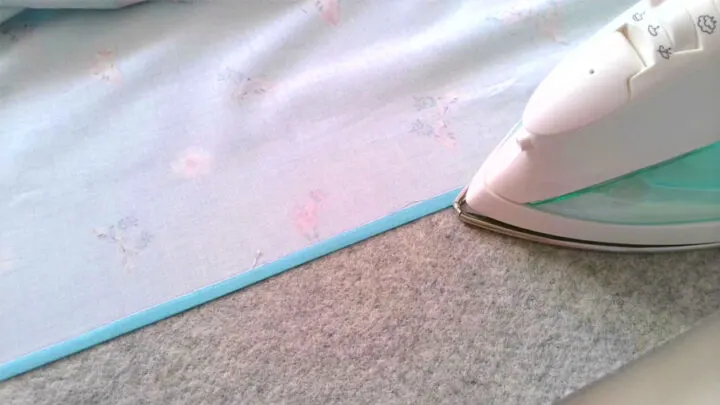 turn under the top edge of the fabric ⅜ “ and pressing it flat. 