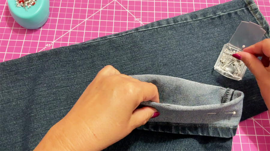 Fold the jeans along the marks and secure the folded section with pins.