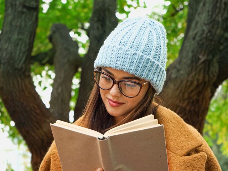 woman with glasses wearing a blue beanie