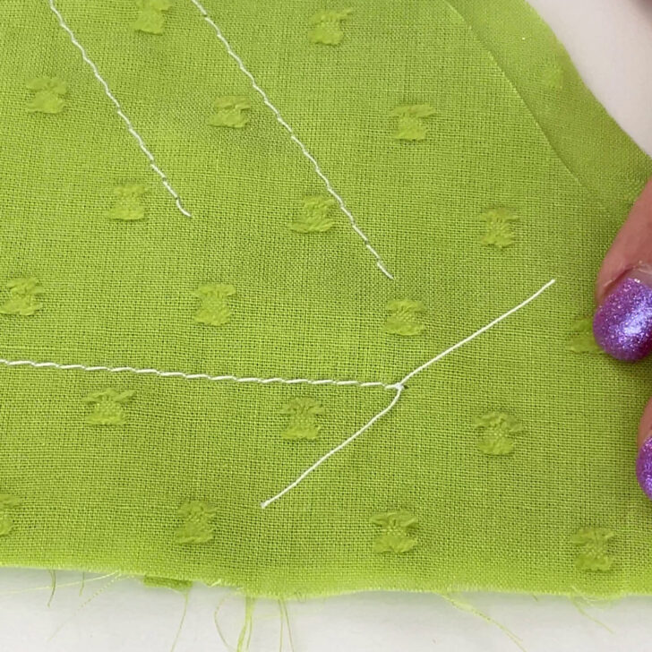 Ensure that you pull the thread through completely to tighten the knot against the fabric, securing the short thread ends.
