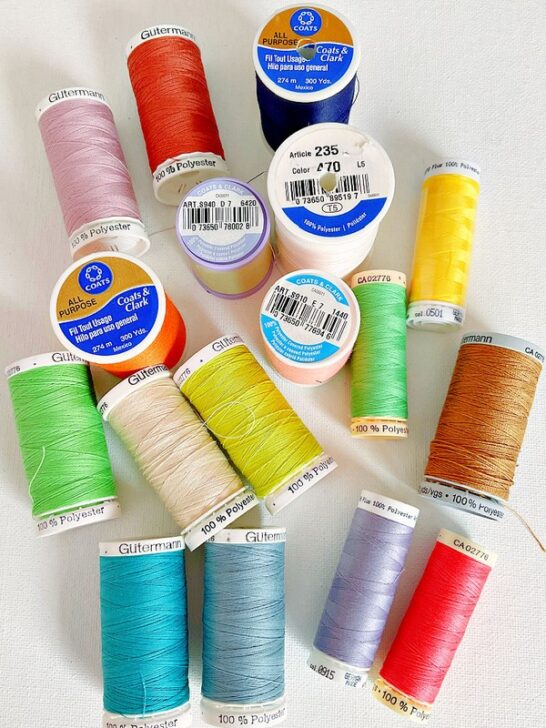 all-purpose polyester thread in various colors, showcasing its versatility and durability for sewing projects. The threads are neatly wound on spools, highlighting their smooth texture and vibrant hues.