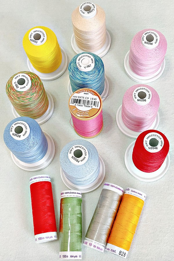 image of cotton thread, showcasing various colors and textures. The threads are neatly wound on spools, highlighting their natural fibers and versatile use in sewing projects.