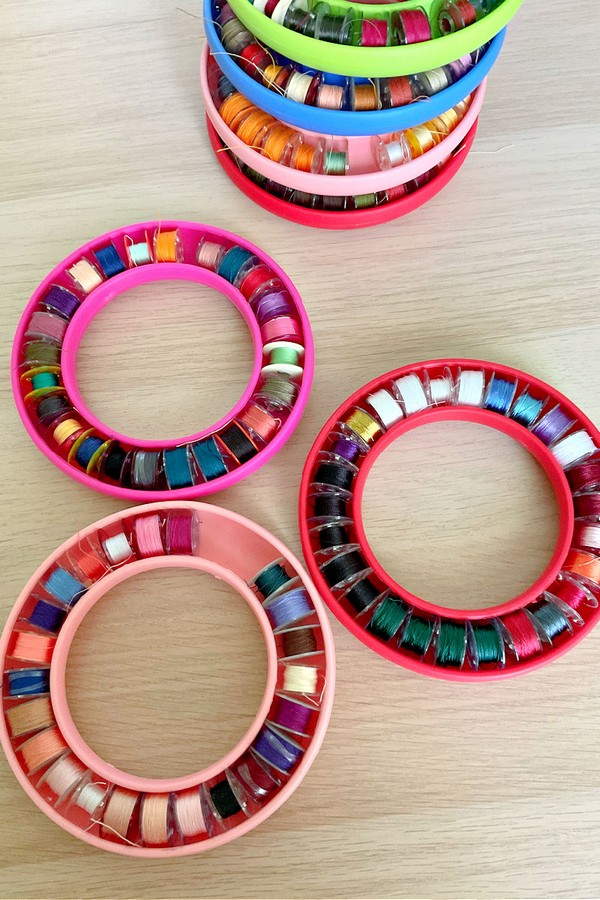 Each bobbin displays different thread colors, including bright reds, soothing blues, earthy greens, and deep purples, showcasing the variety and organization of sewing essentials