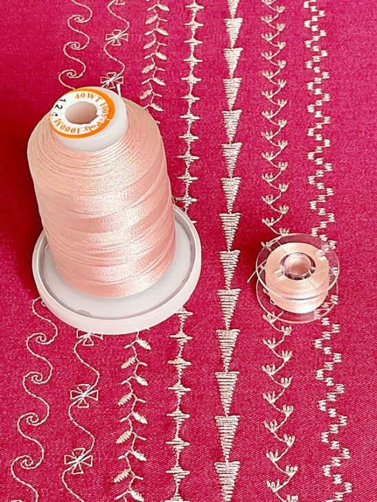 photograph of intricate decorative stitches on red fabric, sewn with delicate light pink thread, enhancing the fabric with subtle texture and artistic detail