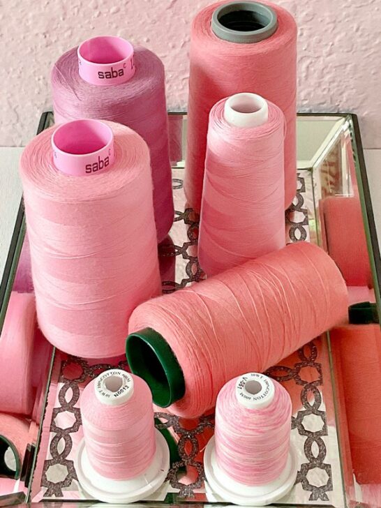 Close-up view of a collection of pink sewing threads, featuring a spectrum of hues