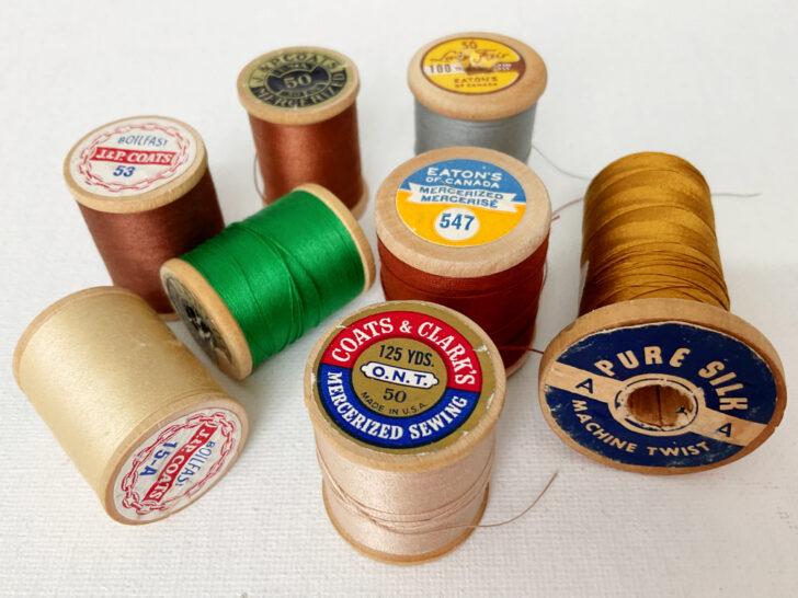 Each spool is intricately labeled with old markings, evoking a sense of historical craftsmanship and artistic variety in sewing supplies