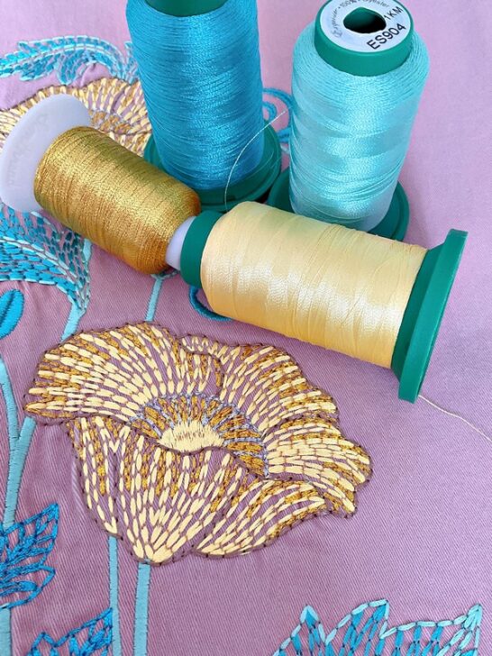 image of a flower embroidery featuring vibrant yellow and teal threads intertwined with shimmering golden metallic thread, highlighting intricate detail
