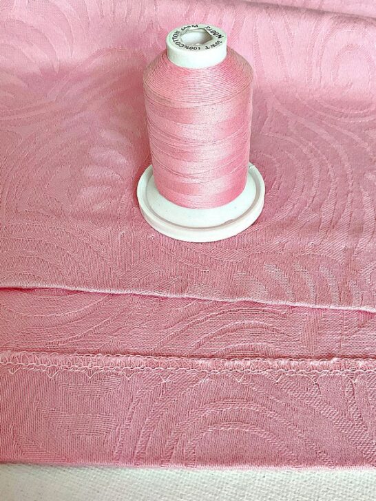 Close-up image showing a nearly invisible hem crafted with thread that matches the fabric's color, demonstrating expert sewing technique and seamless integration