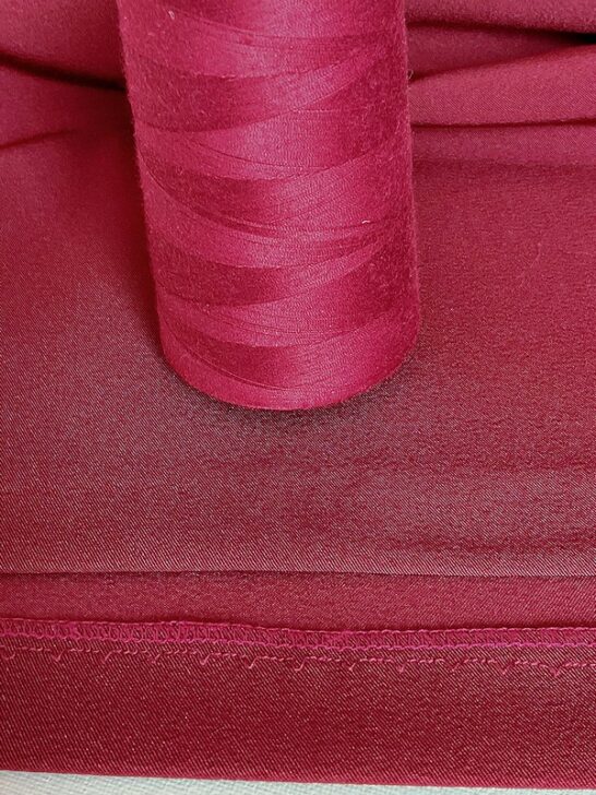 Close-up image of an invisible hem on a skirt, meticulously sewn with thread that perfectly matches the fabric, highlighting expert craftsmanship and seamless finishing.