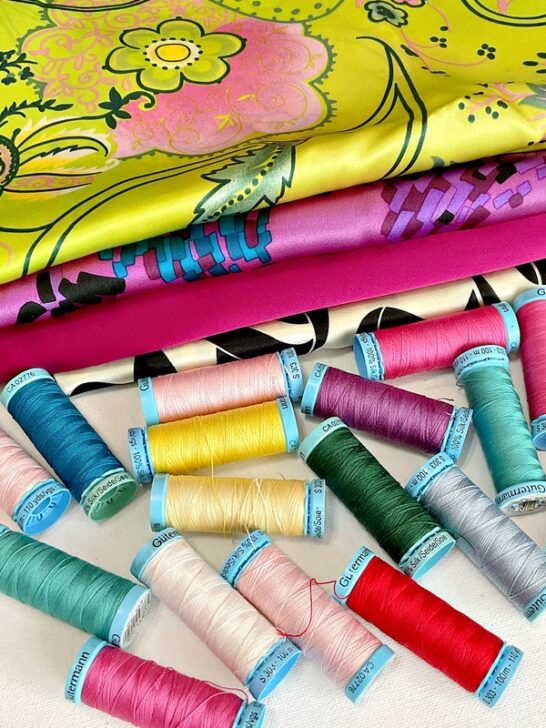 spools of Gutermann silk thread in various colors, accompanied by pieces of vibrant silk fabric