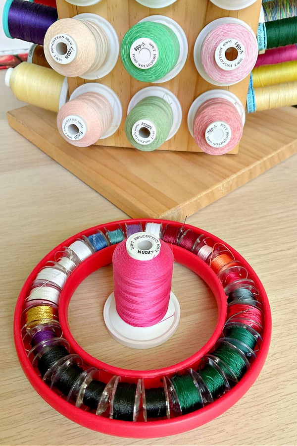 Close-up image of a holder displaying a variety of bobbin threads. Each bobbin showcases different thread colors and textures, organized neatly on the holder.