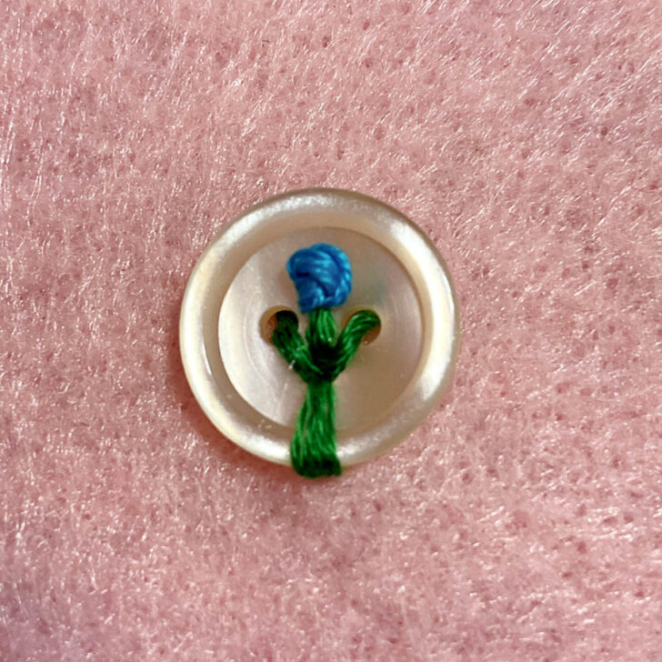 A button showcasing a vibrant blue flower with longer stem