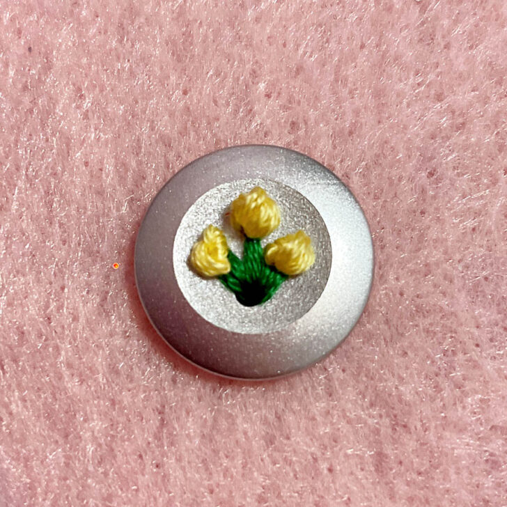 Three yellow flowers on a golden button on my blouse