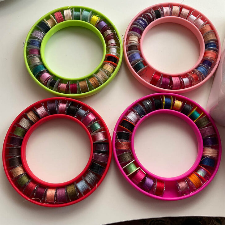 A set of four bobbin holder, each featuring unique, colorful bobbin