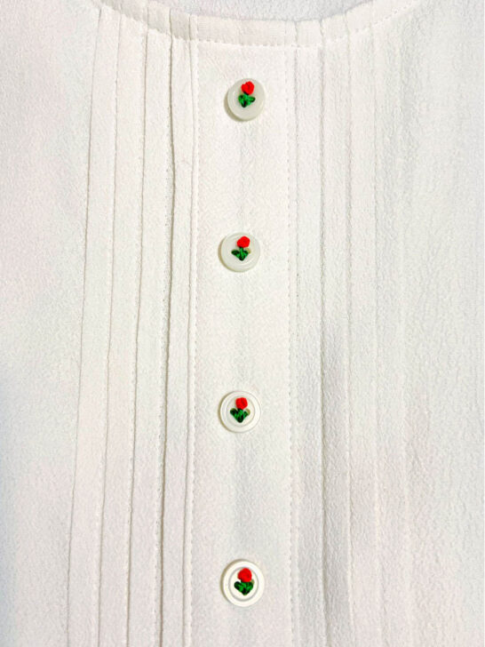 Close-up of a white shirt highlighting the floral buttons
