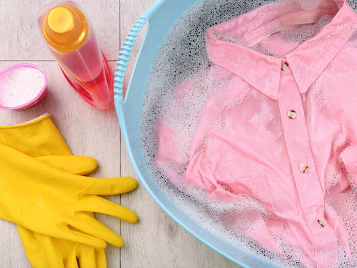 vibrant pink shirt, yellow rubber gloves, and a bottle of liquid cleaner arranged on a table