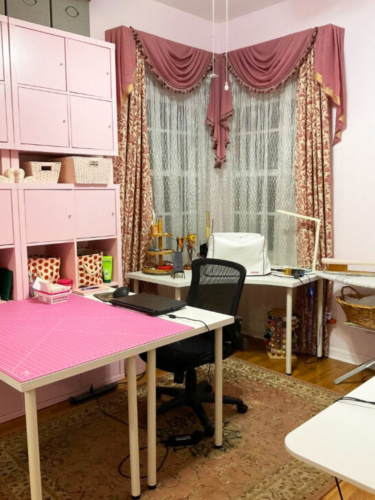 A charming pink and white sewing room with a desk and chair