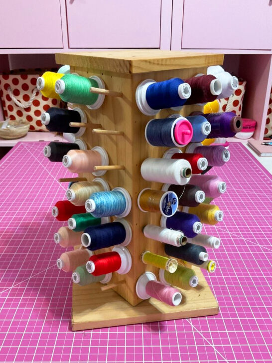 A rustic wooden stand adorned with vibrant spools of thread, perfect for sewing room decor