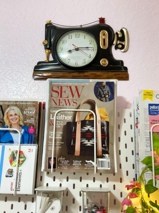 A sewing machine, clock, and magazines displayed on a pegboard, contributing to a stylish and organized sewing room decor