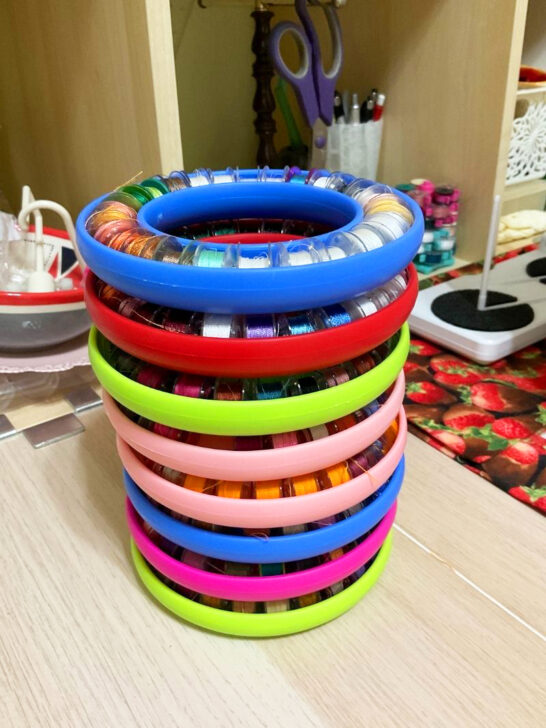 A vibrant stack of bobbin holder displayed on a table in a sewing room, showcasing various colors and designs