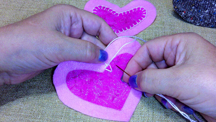 Hands stitching pink felt hearts