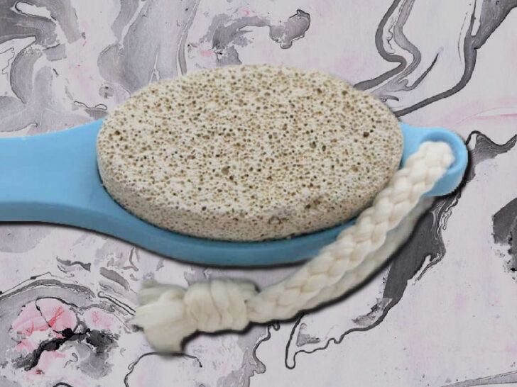 A blue-handled pumice stone with a braided white cord, shown against a marbled black-and-pink background.