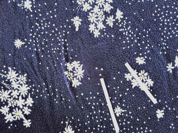 A fabric surface showing two distinct areas after using a pumice stone. One area is lint-free, while the other has visible fuzz and lint.