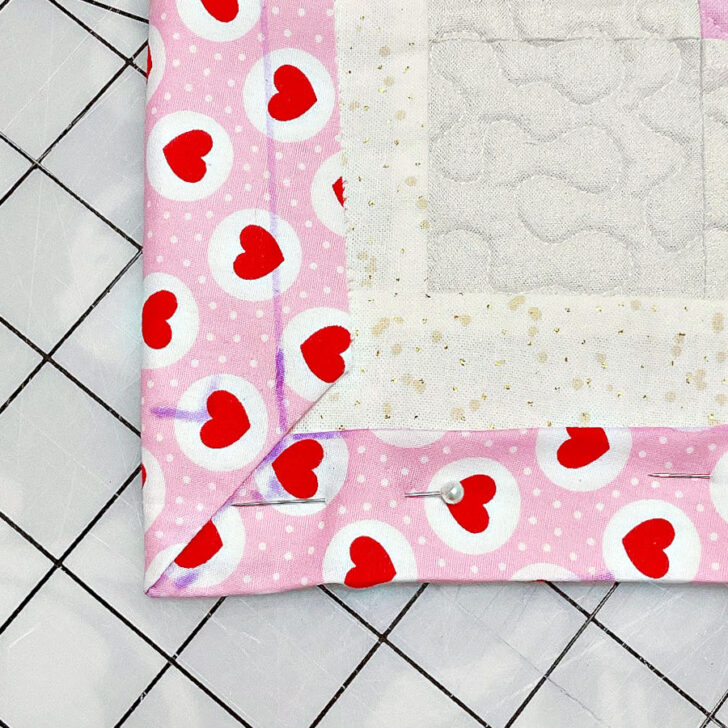 Fold the raw edge of the backing fabric under by 1/2 inch to create a neat seam. Pin the folded edge in place, working your way around the quilt.