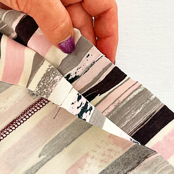 Start pinning stretch fabric. Take a pin and insert it exactly into the seam where the left needle of the serger stitched.