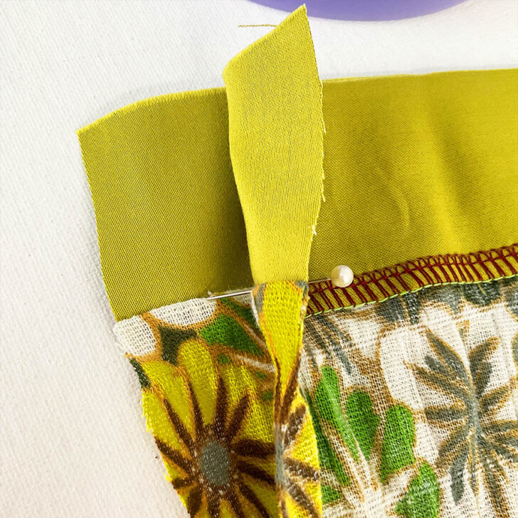 Start pinning. Take a pin and insert it exactly into the seam where the left needle of the serger stitched.