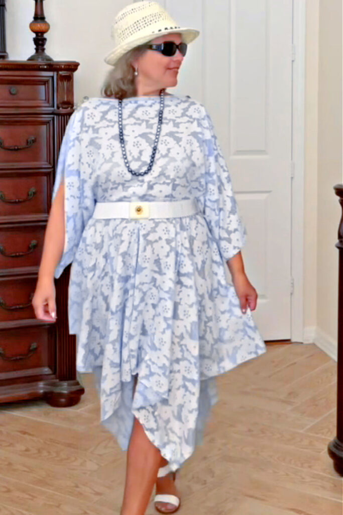 A flowy blue and white dress with a handkerchief hem, styled with a white belt and hat, part of an easy fashion sewing tutorial.