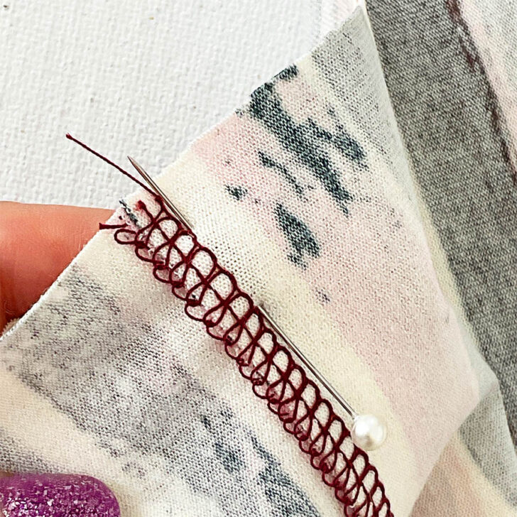 Push the pin back through the first fabric, ensuring it is inserted precisely into the seam line. This creates a stable connection between the two pieces