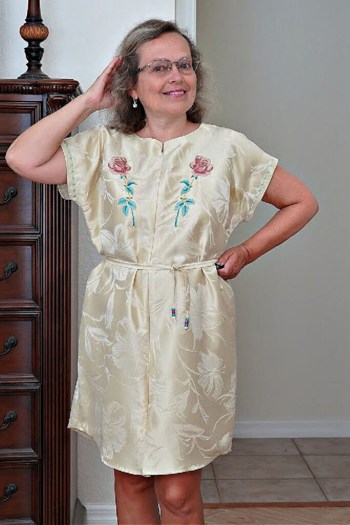 A white silk dress with floral embroidery and a zipper front, part of a fashion sewing tutorial for creating elegant garments.