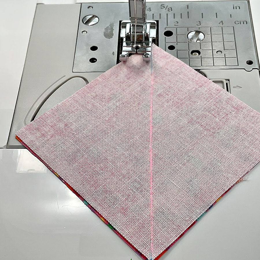 Image shows the beginning of the first stitch for a half square triangle