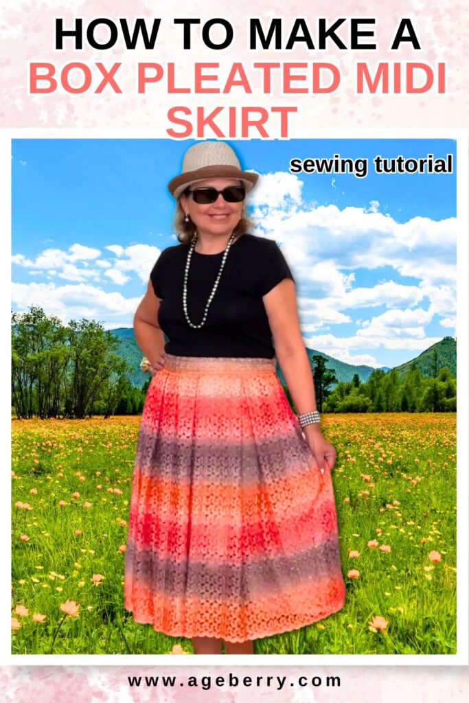 A woman wearing a handmade box-pleated midi skirt in a vibrant ombré pattern of red, orange, and brown. She pairs it with a black top, sunglasses, a pearl necklace, and a straw hat, standing in front of a bright outdoor scene with mountains and a field of flowers. The text overlay reads, "How to Make a Box Pleated Midi Skirt - Sewing Tutorial," with the website ageberry.com at the bottom.