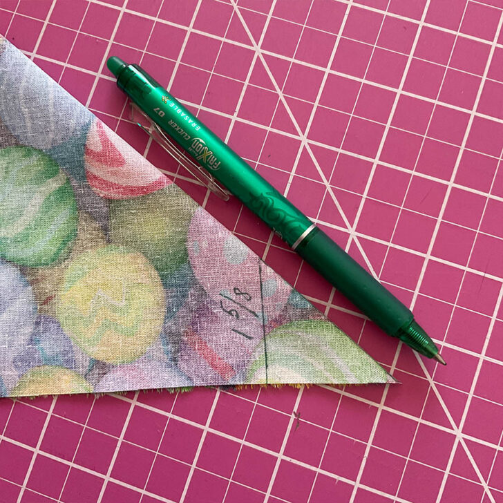 Image shows the fabric folded at the corner in preparation for sewing a mitered corner. A marking pen is visible also.