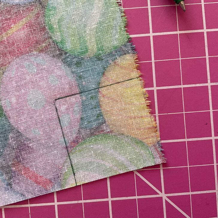 Square marking on a corner of the backing fabric in preparation for sewing a mitered corner