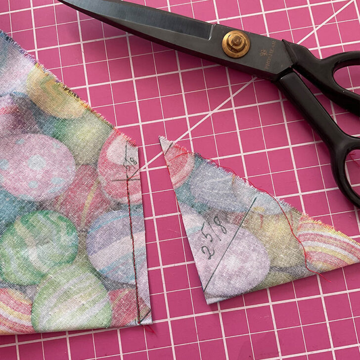 Image shows the corner after being sewn and after cutting the excess material. A pair of tailor's scissors is also in the foreground