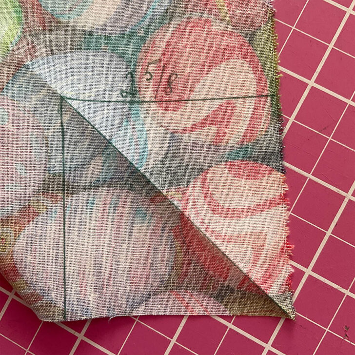 Image shows the diagonal mark and fold on the backing fabric in preparation for sewing a mitered corner