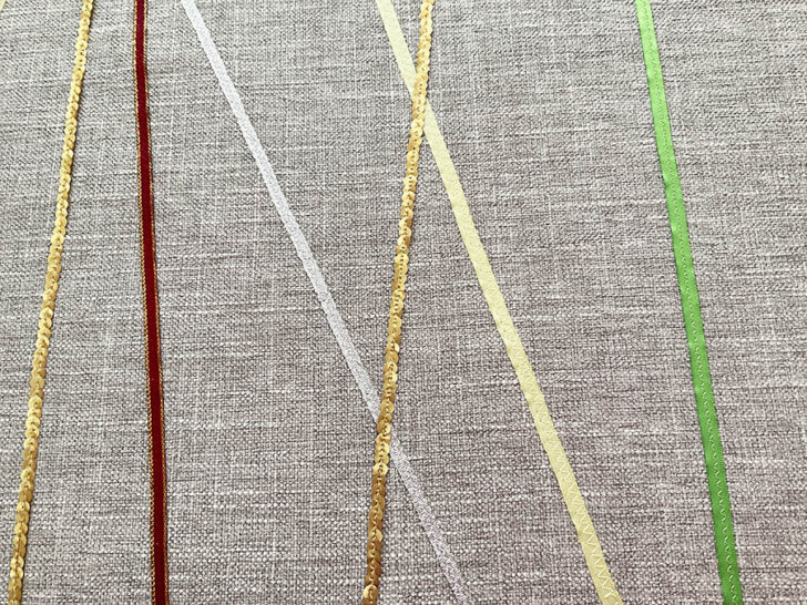 Image shows a close up of various decorative and sequin ribbons arranged for the table runner after pressing