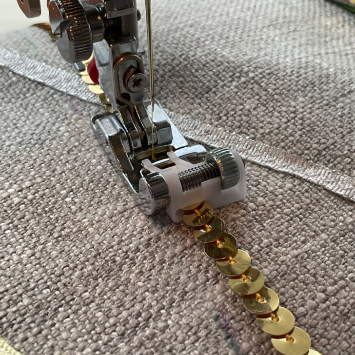 Image of the sequin ribbon foot installed on a sewing machine and sewing a sequin ribbon