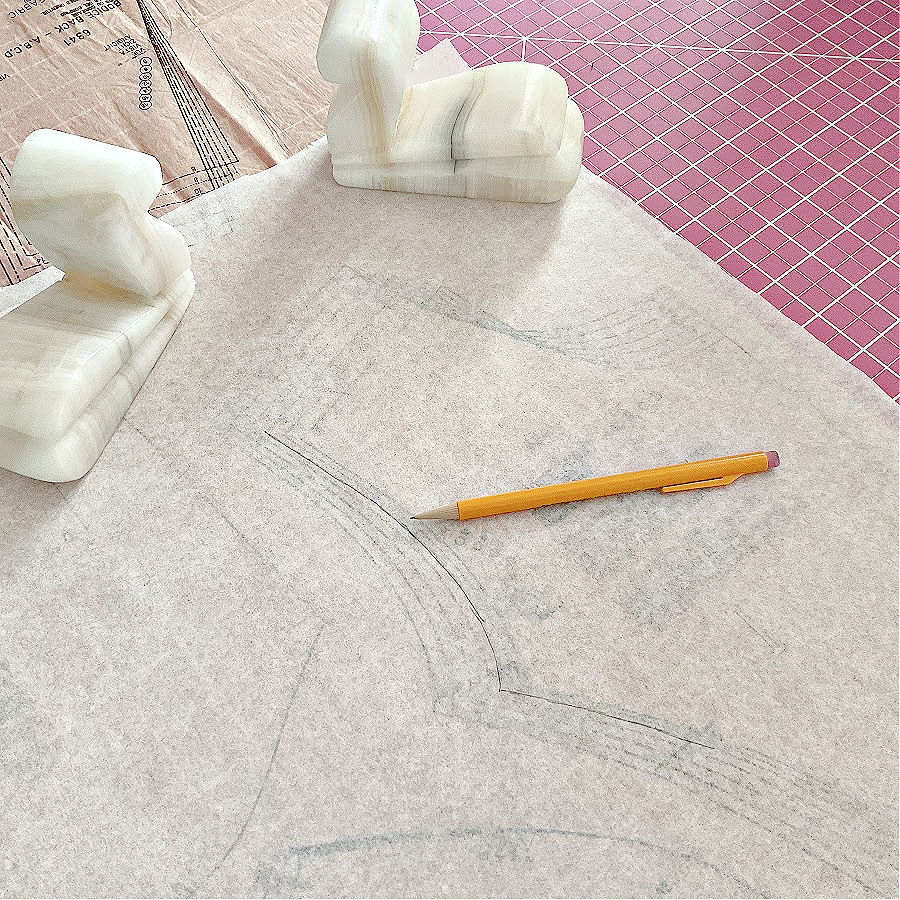 A piece of medical exam paper used for tracing patterns held in place by two stone weights. A mechanical pencil is seen also in the image