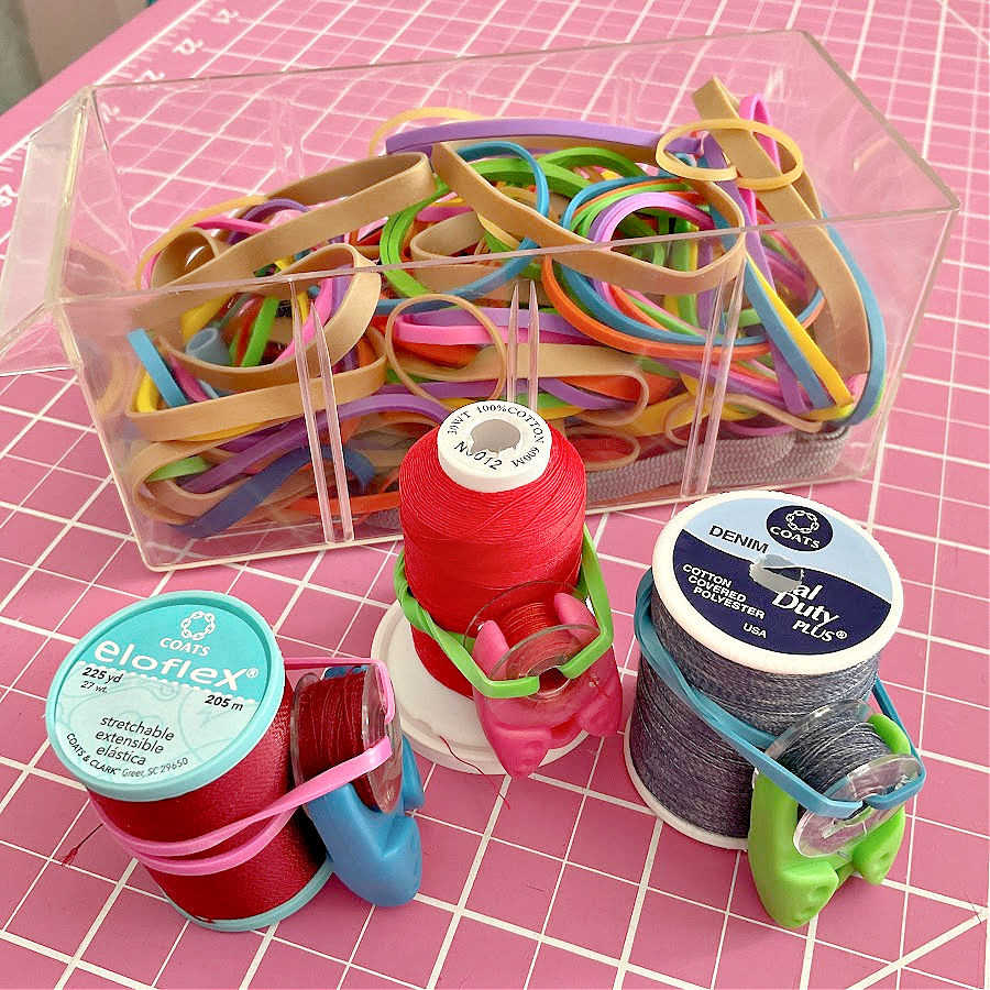 Multicolored rubber bands in a container and exampolesof usage to hold onto threads and bobbins