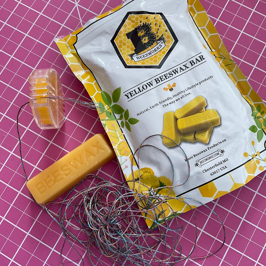 A beeswax package and an applicator box with beeswax showing how beeswax is applied to thread for sewing