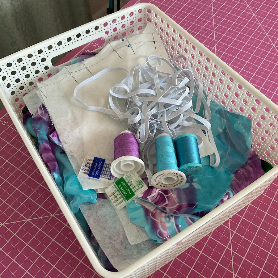 A plastic low profile basket filled with sewing notions and tools
