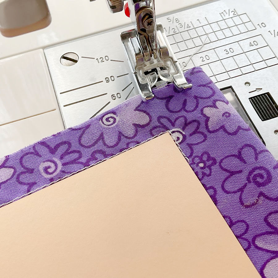 A cardboard corner template being used as a guide for sewing around a corner